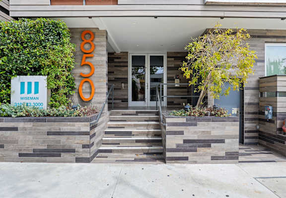 the front of a building with stairs and a sign