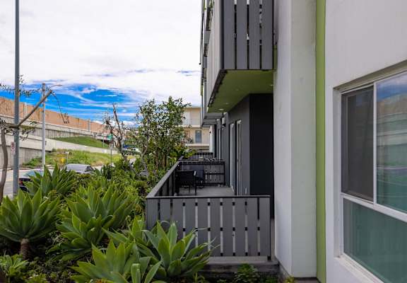 a house with a balcony and plants in front of it