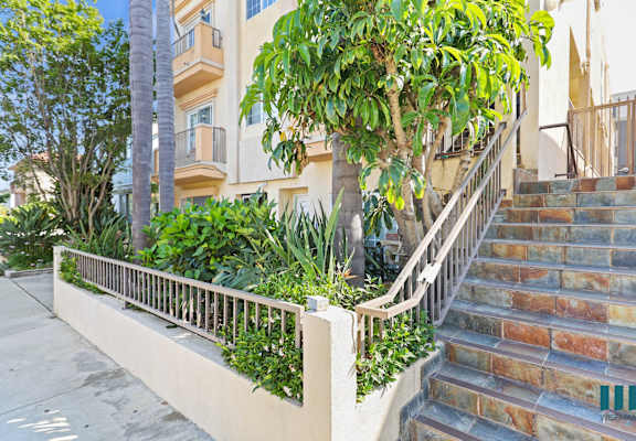 A building with a staircase and a tree in front of it.