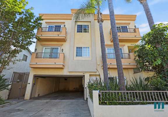 A building with a garage and palm trees in front.