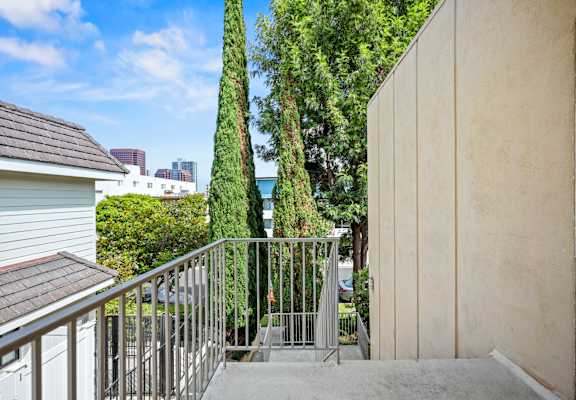 A balcony with a metal railing and steps leading down to a concrete floor.