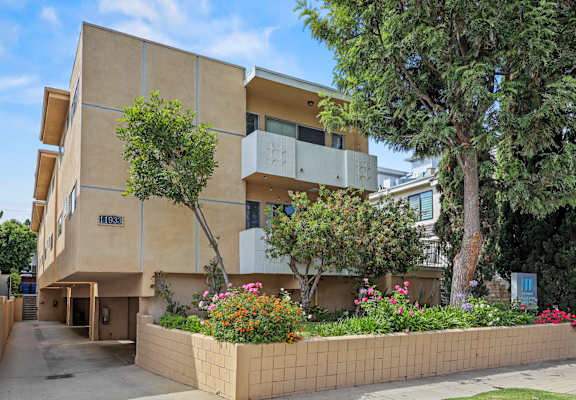 A modern building with a beige facade and a garden in front.