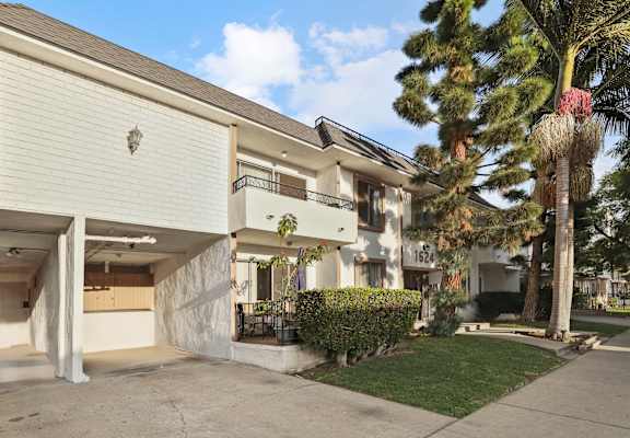 A two-story building with a garage on the first floor and a balcony on the second floor.