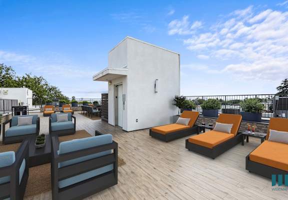 a rooftop patio with couches and chairs and a building in the background