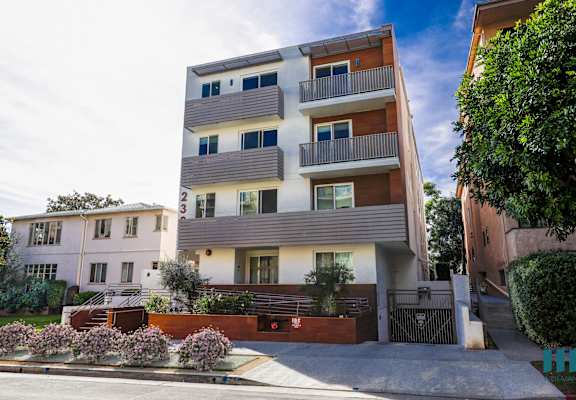 a white apartment building with balconies and a sidewalk