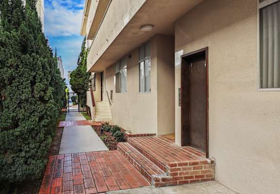 A building with a brown door and a brick pathway leading to it.