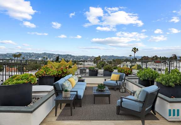 a roof terrace with blue and yellow chairs and potted plants