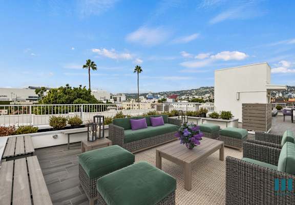 A patio with a table and chairs overlooking a cityscape.