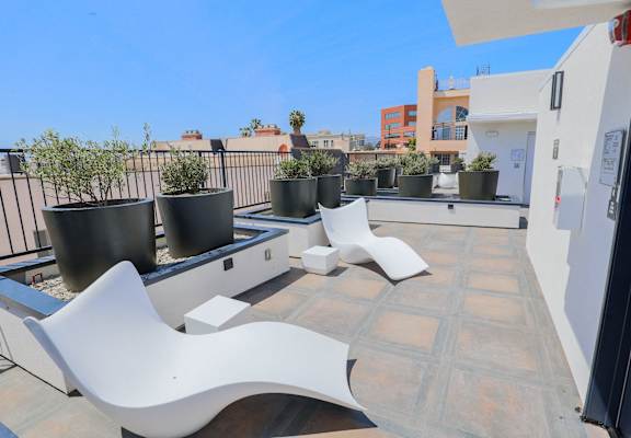 a roof terrace with two white chairs and potted plants