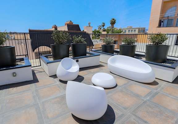 a roof terrace with white chairs and potted plants