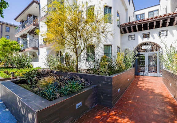the front yard of an apartment building with a pathway and plants