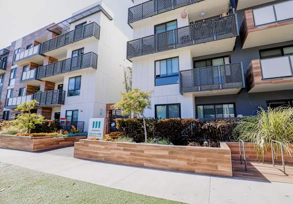 an apartment building with a large wooden planter in front of it