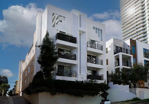 A white building with the letters "WF" on the side is surrounded by greenery and other buildings.
