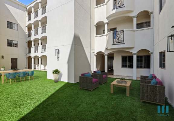 a courtyard with a lawn and chairs in front of a building