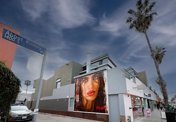 A large billboard with a woman's face on it is on the side of a building.