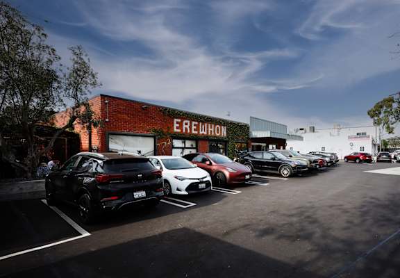 A parking lot with cars parked in front of a building with the word EREWHON on it.