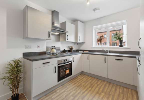 A modern kitchen with wooden floors and stainless steel appliances.