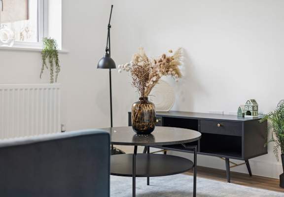 A black table with a vase and a lamp on it.
