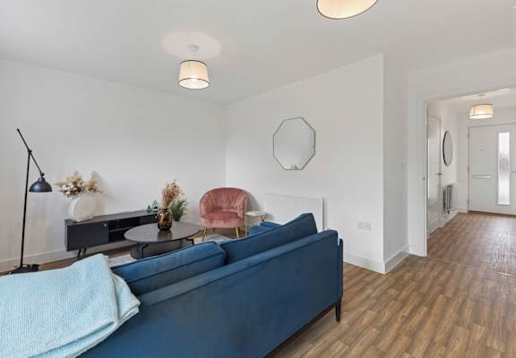 A blue sofa with a light blue blanket on it in a room with a wooden floor.