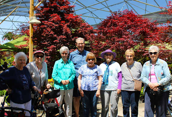 A group of elderly people posing for a photo in a garden.