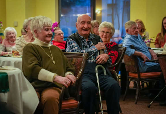 a group of elderly people sitting at a table