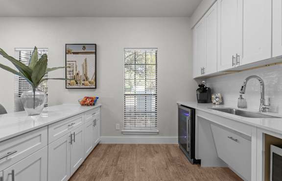 A kitchen with white cabinets and a wooden floor.