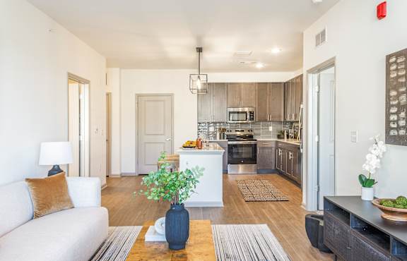 A modern kitchen with a white couch and a blue vase on the coffee table.