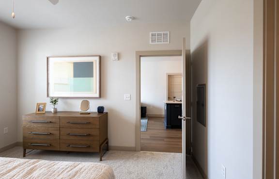 A bedroom with a bed, dresser, and painting.