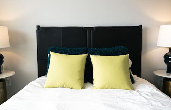 A bed with two yellow pillows and a black headboard.