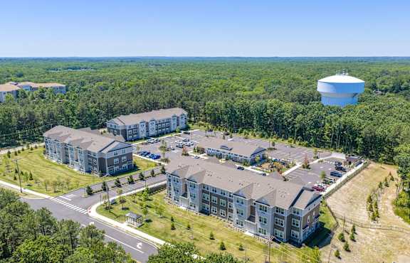 A large building complex surrounded by trees and a parking lot.