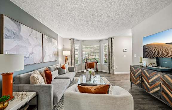 A living room with a grey couch, a white armchair, and a wooden coffee table.