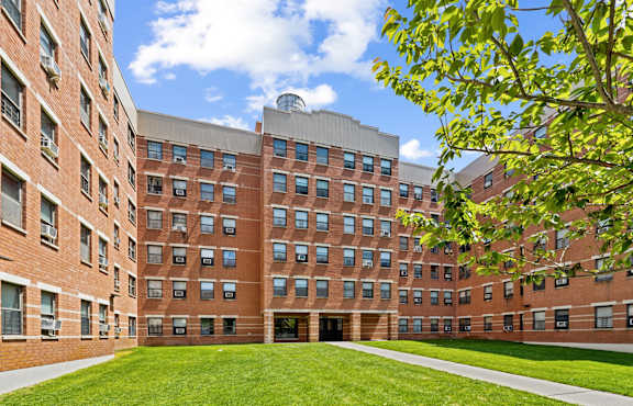 A large brick building with a green lawn in front.