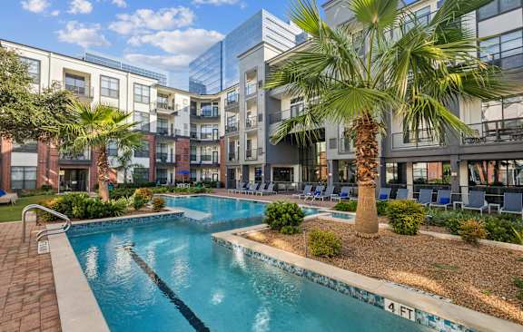 a swimming pool in front of a building with palm trees at The Atlantic Memorial, Houston, 77079