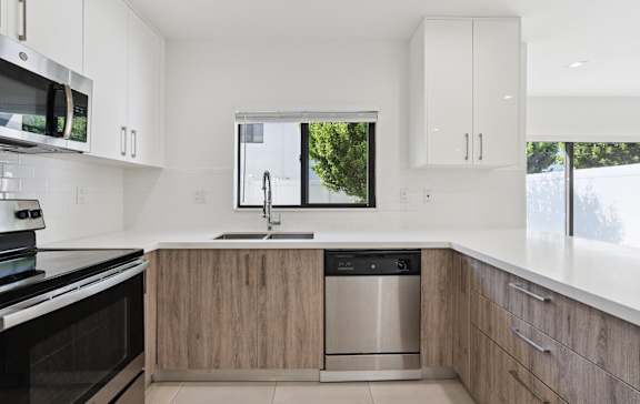 A modern kitchen with a stainless steel dishwasher and wooden cabinets.at The Villages at Miami Gardens, Miami Gardens, 33056