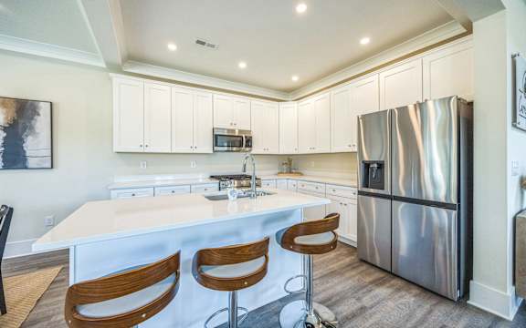 A kitchen with a white island and stainless steel appliances.