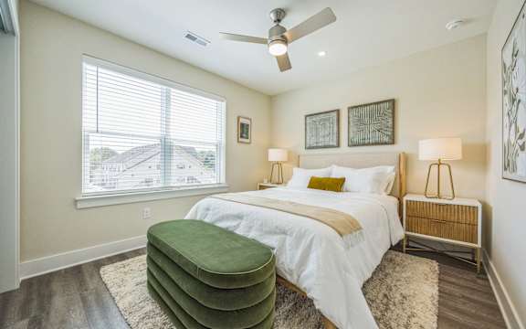 A bedroom with a large bed and a green ottoman.