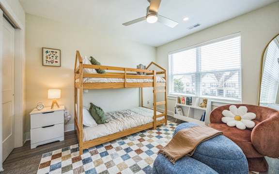 A bedroom with a bed, chair, and a ceiling fan.
