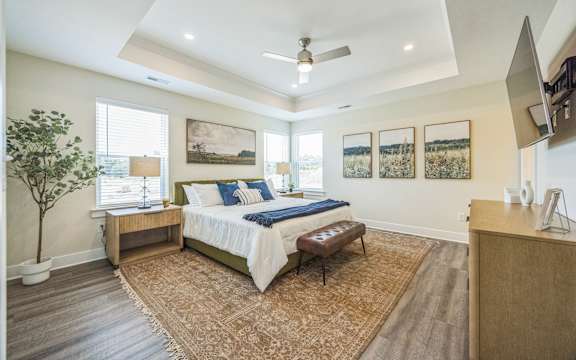 A bedroom with a bed, a bench, and a tree.