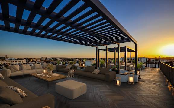 A sunset view from a rooftop patio with a variety of seating options.