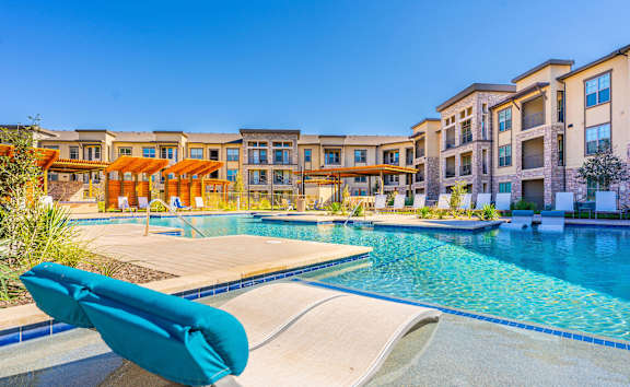 A poolside lounge chair overlooks a swimming pool at a resort.