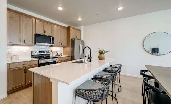 A kitchen with a white countertop and black chairs.
