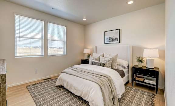 A bedroom with a large bed and a window with blinds.