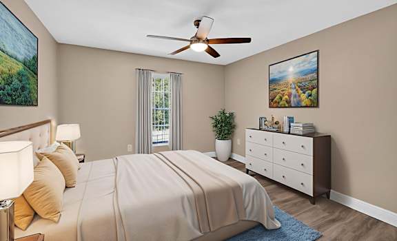 A bedroom with a large bed, a ceiling fan, and a painting on the wall.