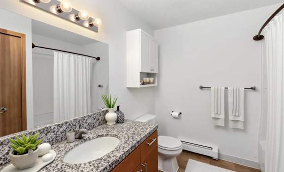 A bathroom with a white toilet, a sink, a mirror, and a towel rack.