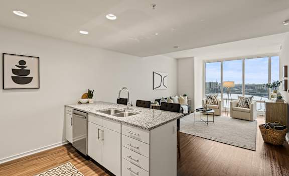 A modern kitchen with white cabinets and a large window.