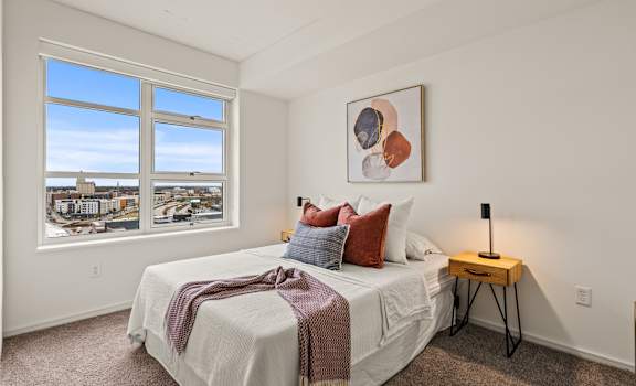 A bedroom with a large bed and a view of the city through the window.