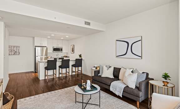 A modern living room with a grey couch, a coffee table, and a dining table with chairs.