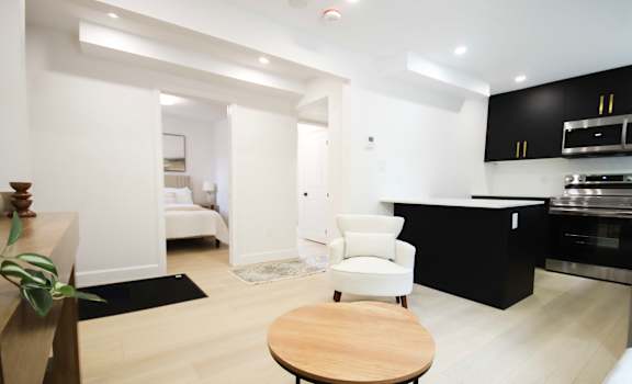 A modern kitchen with a black counter and a white chair.
