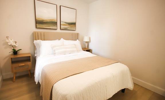 A bedroom with a large bed and two framed pictures on the wall.