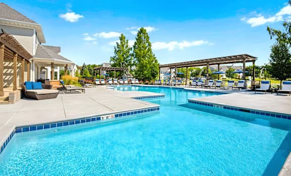 A large outdoor swimming pool with a patio area and a tree in the background.